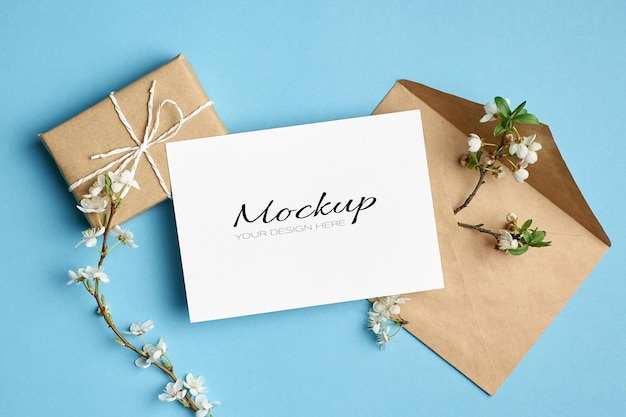 Invitation or greeting card mockup with gift box, envelope and cherry tree twigs with flowers