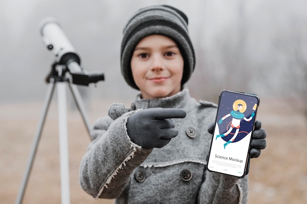 Kid learning science while holding a smartphone mock-up