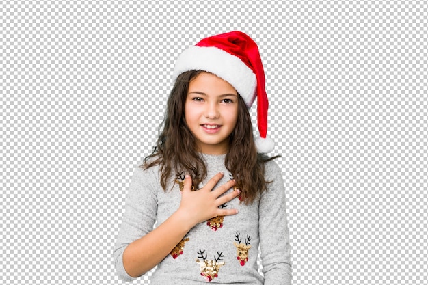 PSD little girl celebrating christmas day laughs out loudly keeping hand on chest.