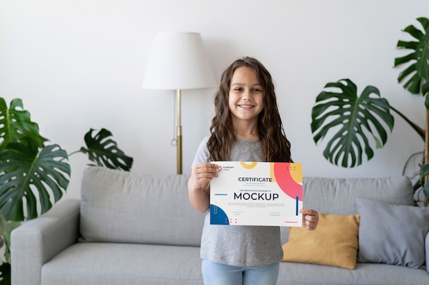 Little girl at home holding a certificate mock-up