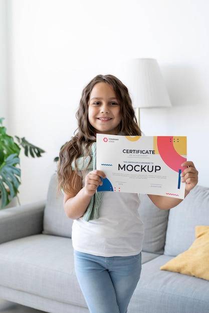 Little girl at home holding a certificate mock-up