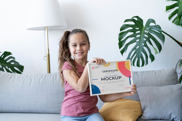 Little girl at home holding a certificate mock-up