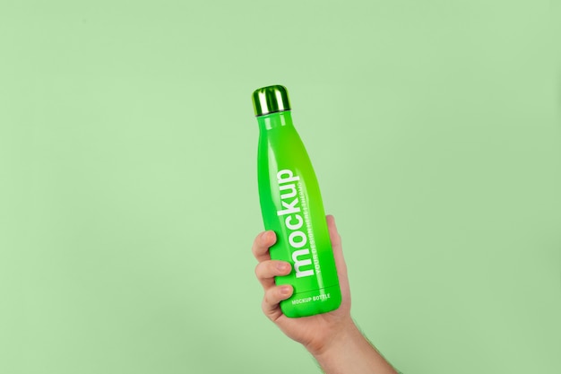 Male hand holding mock-up of green thermos bottle