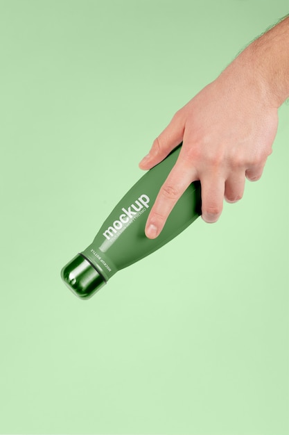 Male hand holding mock-up of green thermos bottle