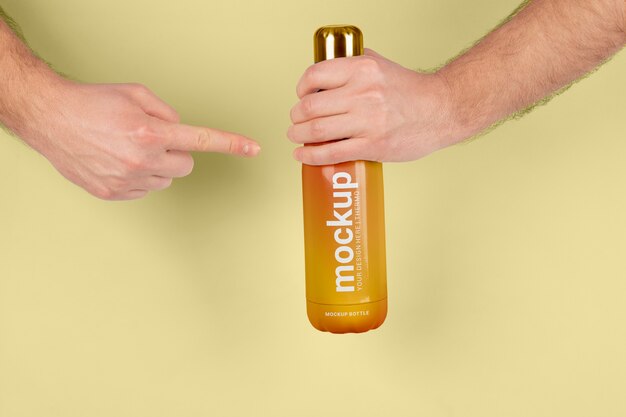 Male hand holding mock-up of orange thermos bottle