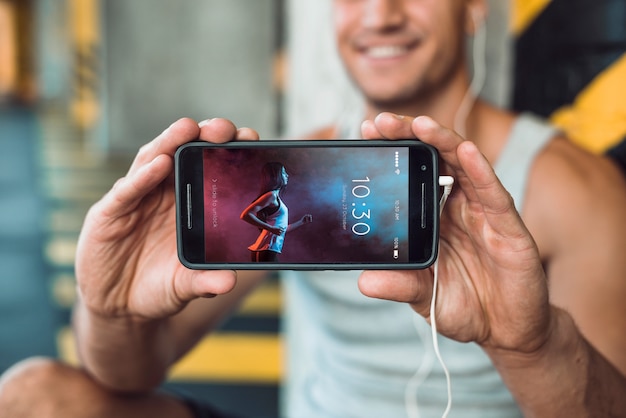 Man in gym holding smartphone mockup