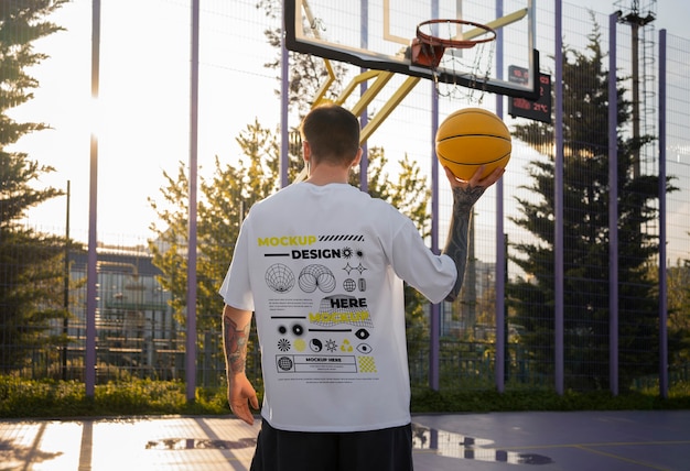 Man wearing cyber street wear t-shirt mock-up with urban design on the basketball court