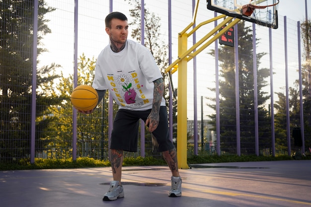 Man wearing cyber street wear t-shirt mock-up with urban design on the basketball court