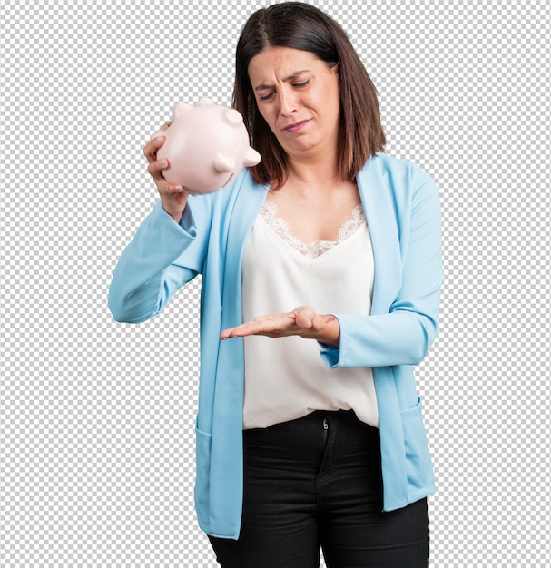 Middle aged woman sad and disappointed, holding a piglet bank, no money left, trying to get something out, face of anger and anguish, concept of poverty