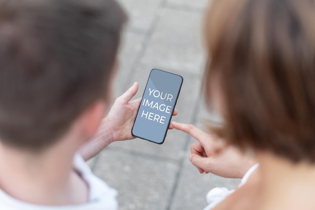 Mock up Man and woman holding a mobile phone in which you can include the image of your choice