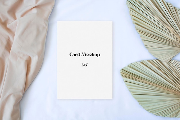 Mockup card with leaf palm and nude fabric on the white background