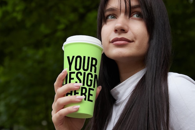 Mockup green paper cup for coffee girl holding in hand closeup changeable color your design