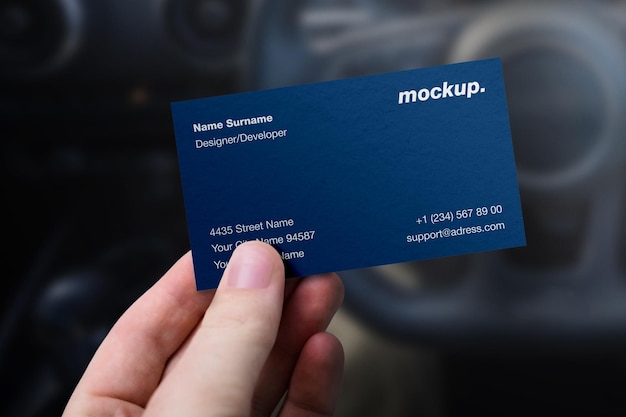 Mockup of hand holding professional corporate stationery business identity card over car wheel