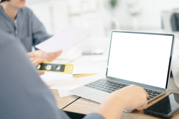 Mockup image of engineers using laptop to drawing design building Project in office