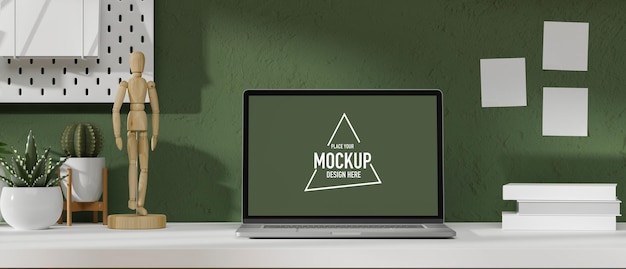 mockup laptop screen in modern workspace with figure plants and decor on white table and green wall