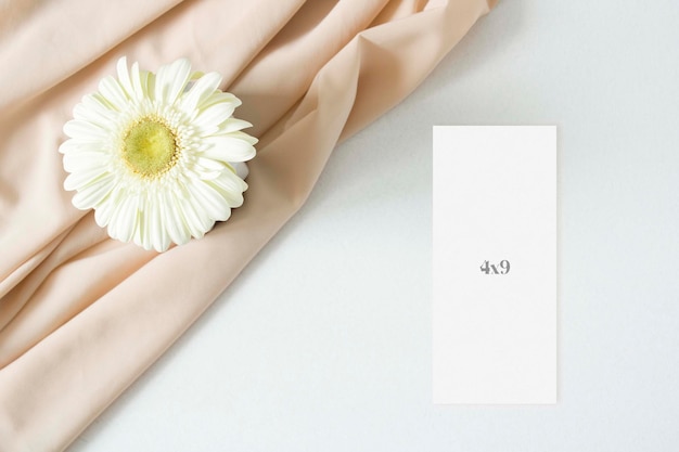 Mockup menu card with gerbera leaves and nude fabric