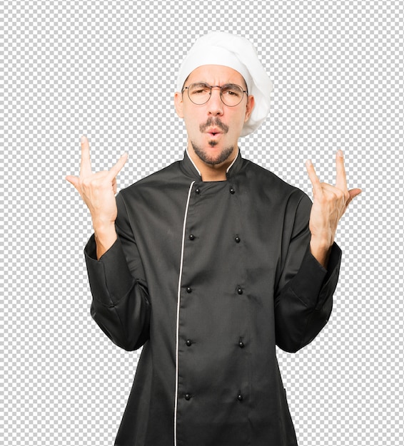 Naughty young chef making a rock gesture