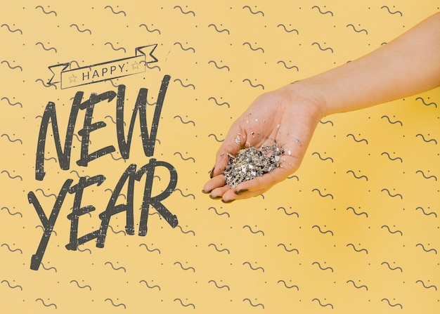 PSD new year lettering with person holding silver confetti