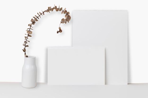 Paper leaning on wall psd mockup with dried plant in vase 