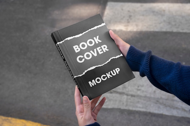 Person holding a book with mock-up cover