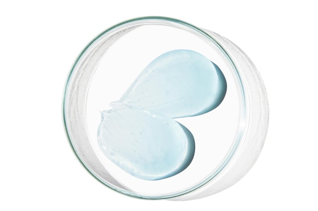 Petri dish with a drop and a smear of a transparent gel or serum on an empty background