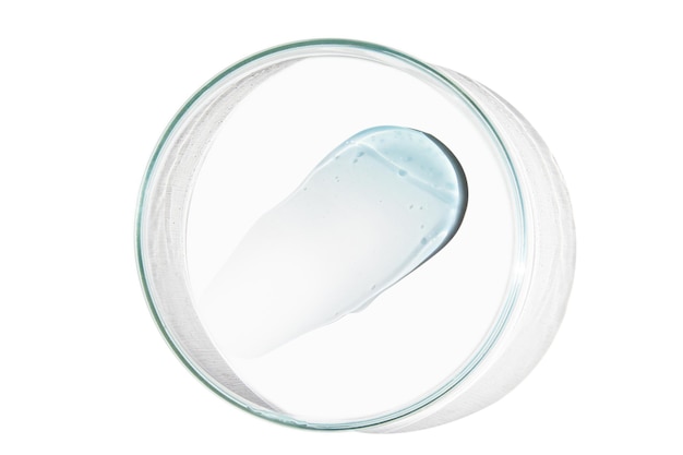 Petri dish with a drop and a smear of a transparent gel or serum on an empty background