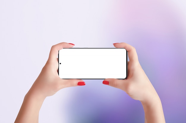 Phone mockup in horizontal position in woman hands. Purple abstract background