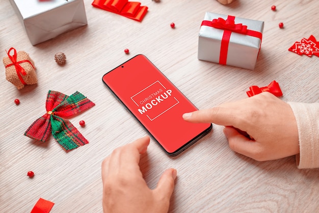 Phone mockup surrounded by Christmas decorations and gifts