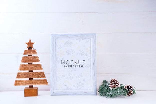 Photo mock up with white frame, wooden tree and pine branches on white wooden background