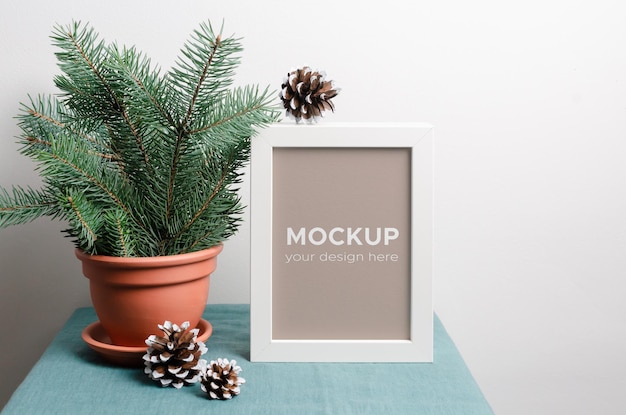 PSD photo or poster frame mockup with fir tree branches and cones in terracotta pot