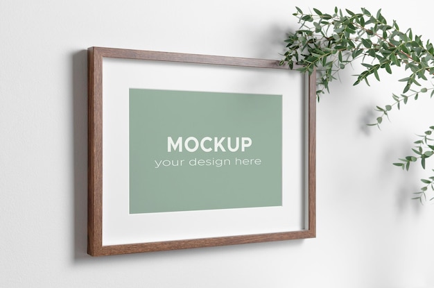 Picture frame mockup on white wall with natural eucalyptus