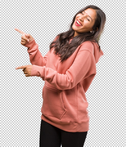 Portrait of fitness young indian woman pointing to the side, smiling surprised presenting something, natural and casual