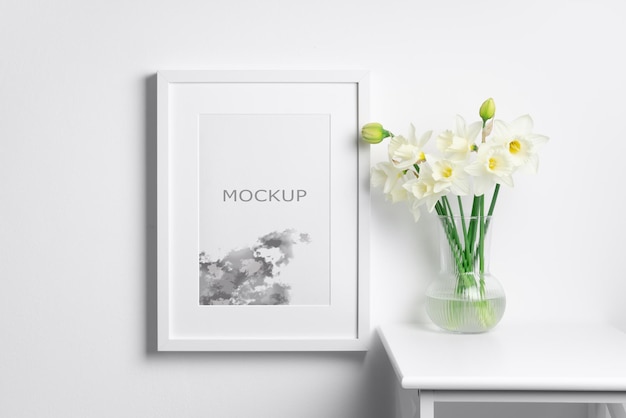 Portrait frame mockup with spring narcissus flowers on white wall