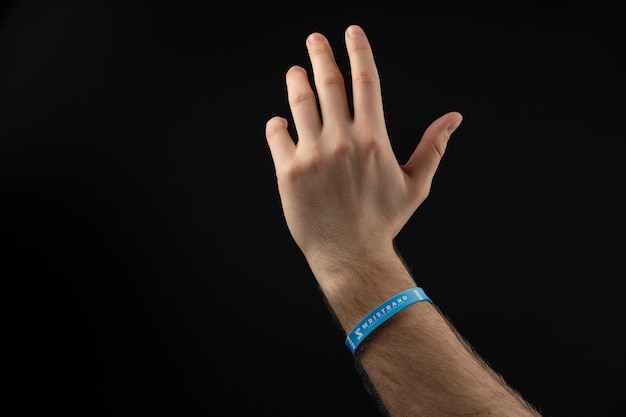 Realistic hand wearing blue bracelet with dark background