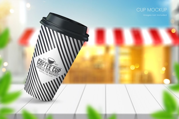 Realistic paper coffee cup mockup on wooden tabletop with blue sky and cafe in background