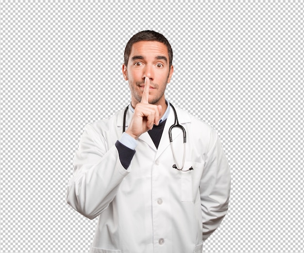 Serious doctor with silence gesture against white background