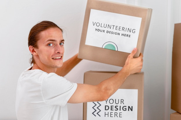 Side view of male volunteer handling boxes with donations