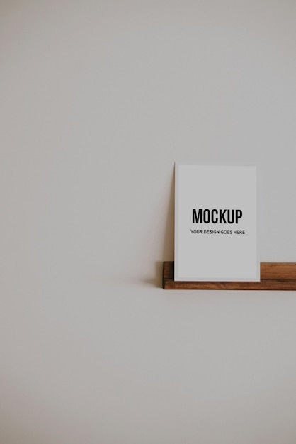 Small paper card on a wooden shelf on an empty wall