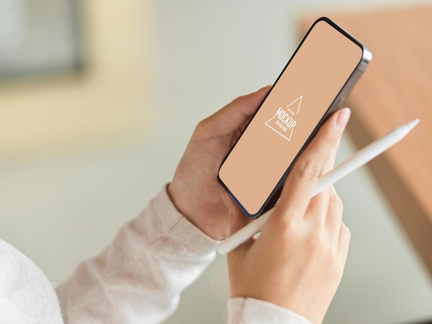 Smartphone mock-up on female hands, holding stylus pen and blurred background