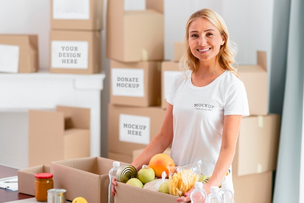 Smiley female volunteer holding donation box with food