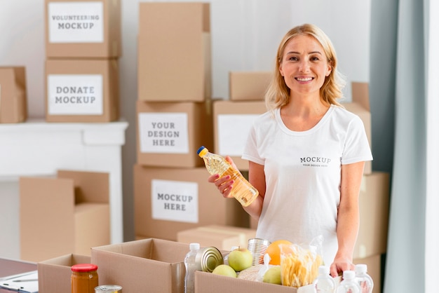 Smiley female volunteer holding provisions before putting them in the box