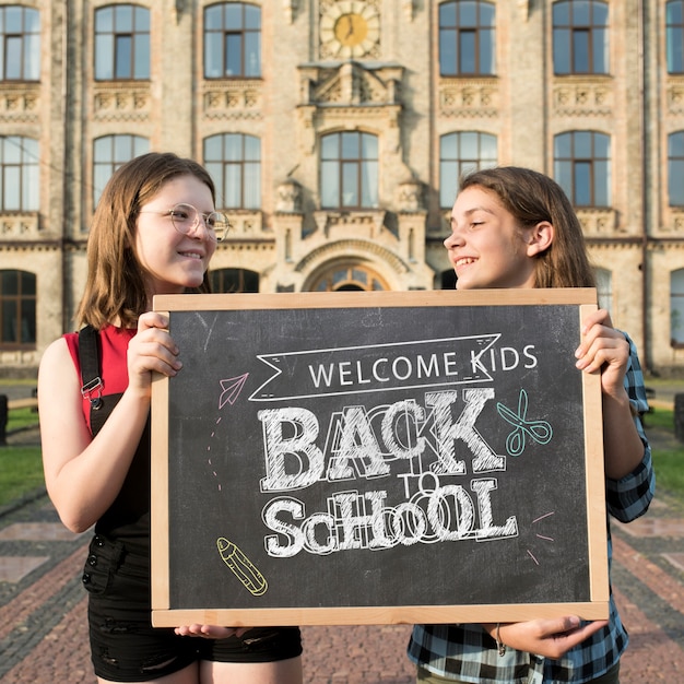 Smiley girls holding a blackboard mock-up