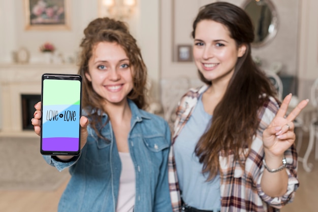 Smiling girls presenting smartphone mockup