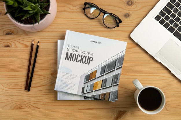 Square book mock-up on wooden desk with stationery