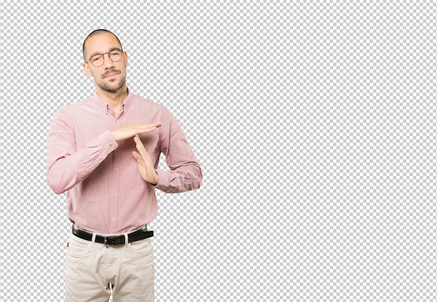 Stressed young man making a time out gesture with his hands