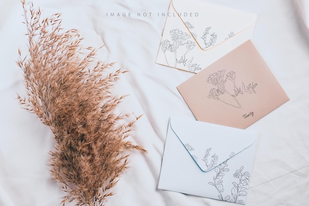 PSD styled craft envelope and white card mockup with dried grass on textile