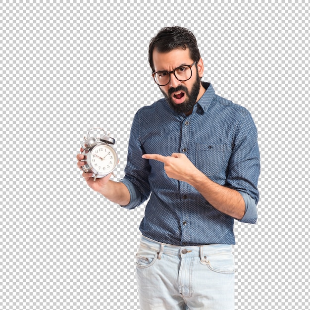 Surprised young hipster man holding a clock