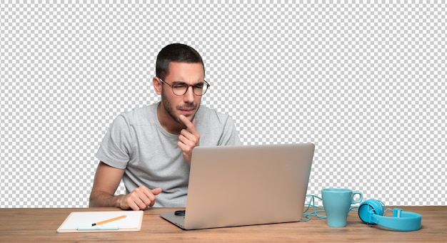 Suspicious young man sitting at his desk