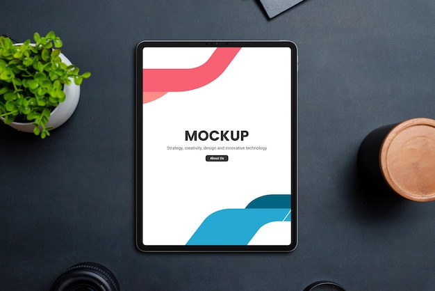 Tablet mockup on black table surrounded by office desk objects