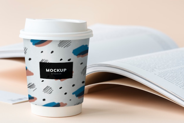 PSD takeaway coffee cup mockup on a table with an open book